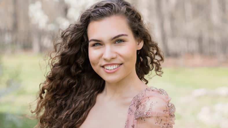 Young smiling woman with curly hair outdoor portrait