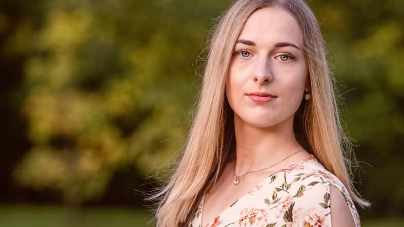 Portrait of a young blonde woman against a defocused landscape. Autumn color shade - image