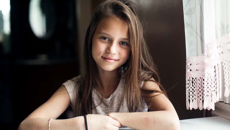 Portrait of cute little girl sitting at the table.