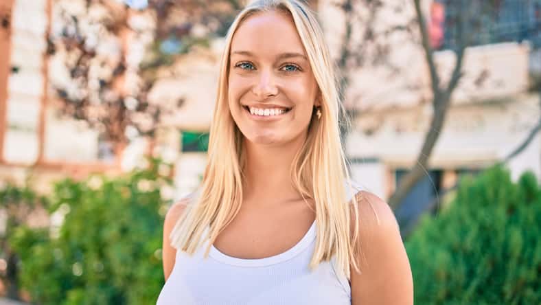Young blonde girl smiling happy walking at the park.
