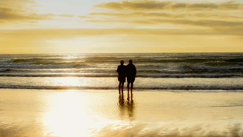 Paras románticas de la edad de jubilación que miran al mar al atardecer