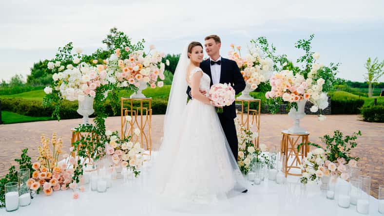 beautiful bride and groom in the wedding ceremony area of live white and pink flowers. decoration and organization of celebrations in the open air.