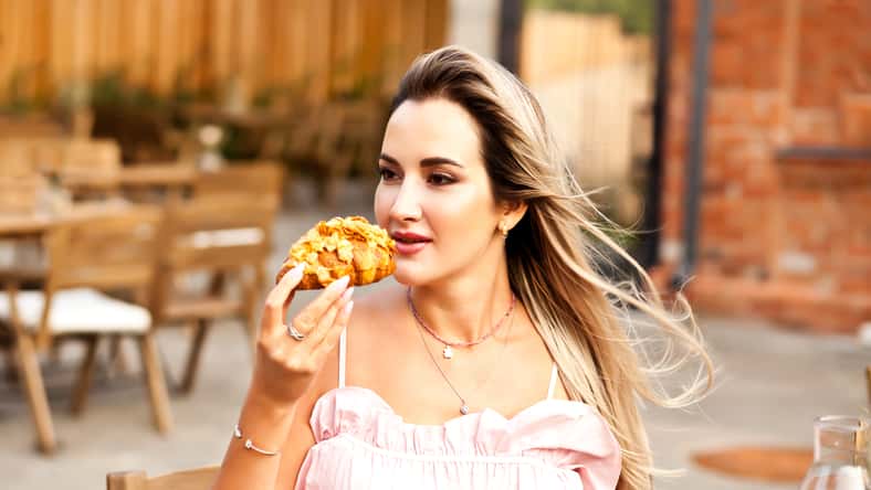 Beautiful woman drinking coffee in a cafe and eating croissant.