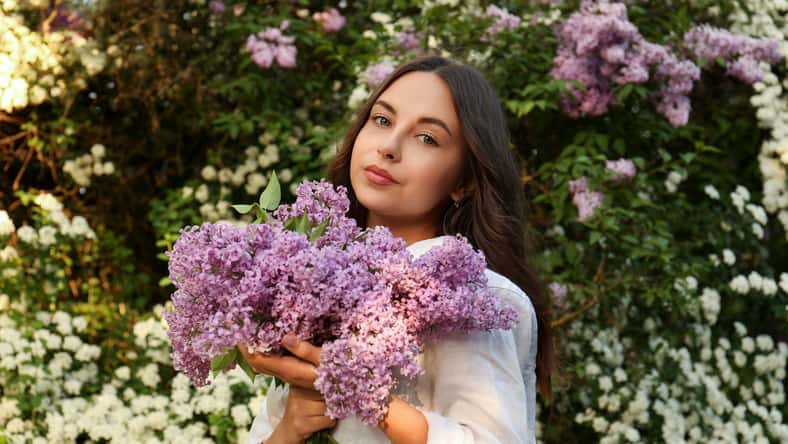 Attractive young woman with lilac flowers outdoors