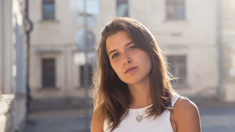 Retrato de una linda chica morena en el fondo de una casa de la ciudad en un día soleado de verano