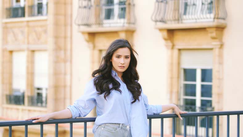 Fashion portrait of beautiful young woman, wearing blue shirt, posing outdoors