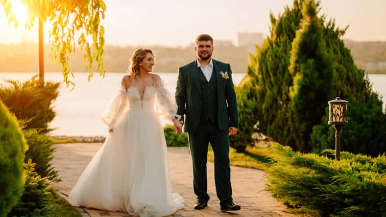 the bride and groom walk holding hands along the path. the concept of trust and a happy family life.