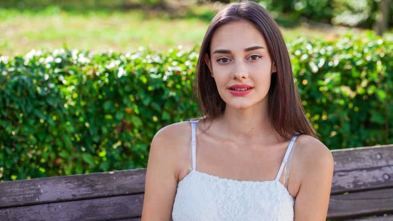 Close up portrait of a young beautiful brunette girl in summer park