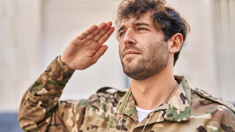 Young man army soldier doing military salute at street