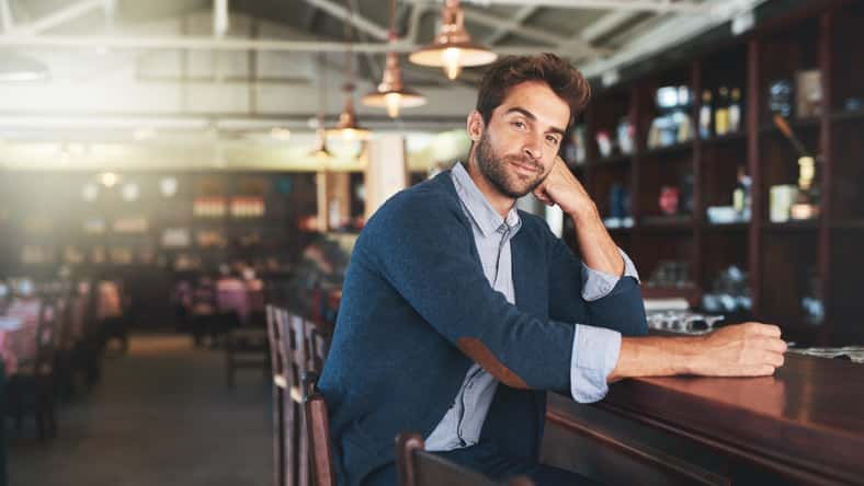 Portrait, relax and business with man, bar and sitting with break and alcohol establishment. Face, person and guy with vacation and peace with entrepreneur and patience with fashion and counter.