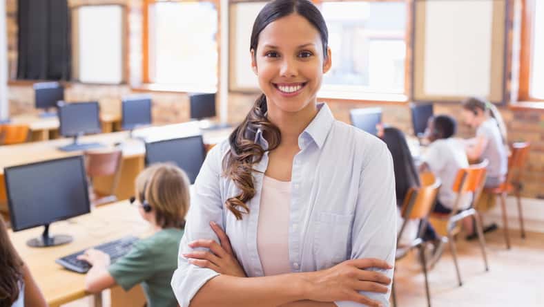 Pretty teacher smiling at camera at back of classroom