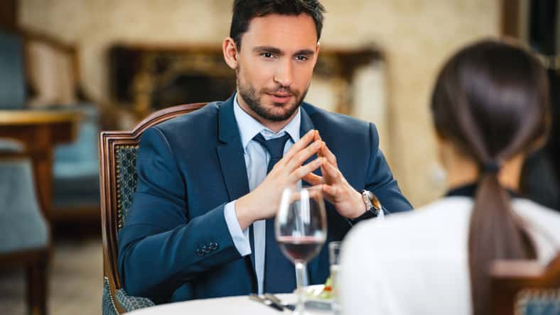 Photo of business meeting in expensive hotel. Young businessman talking with business woman while having dinner