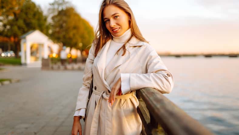 A young woman walks along the embankment and enjoys the warm autumn sunset. Lifestyle, travel, tourism, active life.
