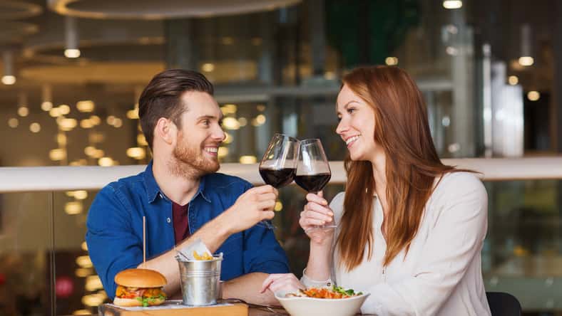 leisure, celebration, food and drinks, people and holidays concept - smiling couple having dinner and drinking red wine at date in restaurant