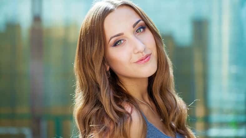 Close up portrait of beautiful young happy brunette woman with fresh and clean skin, summer street outdoors