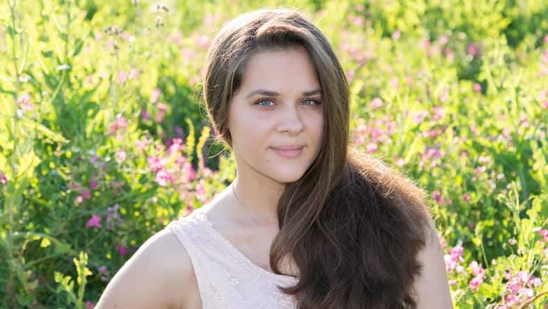 Portrait of a girl of 16 years in the flower meadow