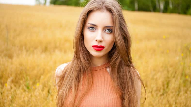Portrait of a young girl on a background of golden wheat field, summer outdoors