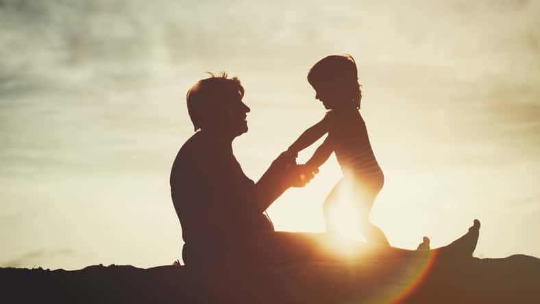 silhouette of grandmother and little granddaughter play at sunset beach