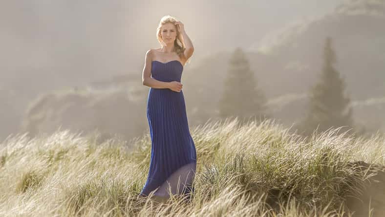 outdoor portrait of young beautiful blonde woman in blue gown posing on natural background