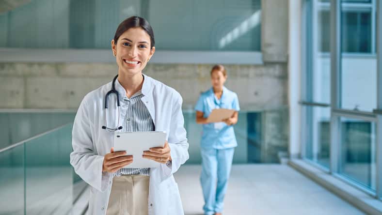 Portrait of smiling female doctor holding tablet in hospital corridor