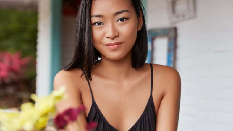 Pleasant looking young Asian woman with attractive appearance, poses indoor in cafeteria, being delighted to spend vacation in unknown country. People, facial expression and lifestyle concept