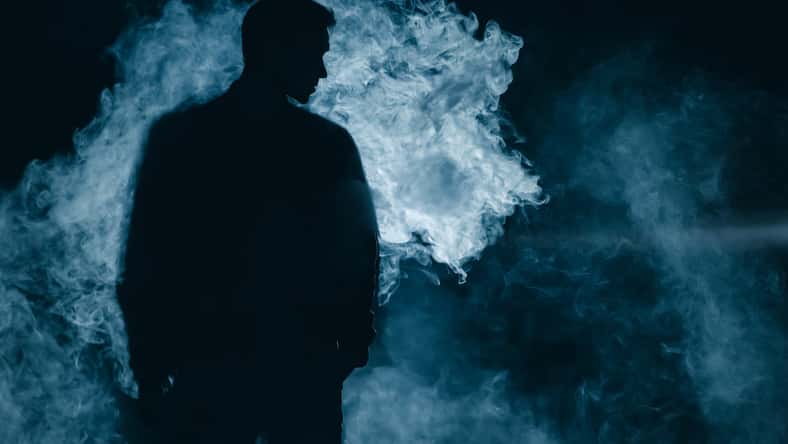 The man silhouette standing in the smoke. evening night time