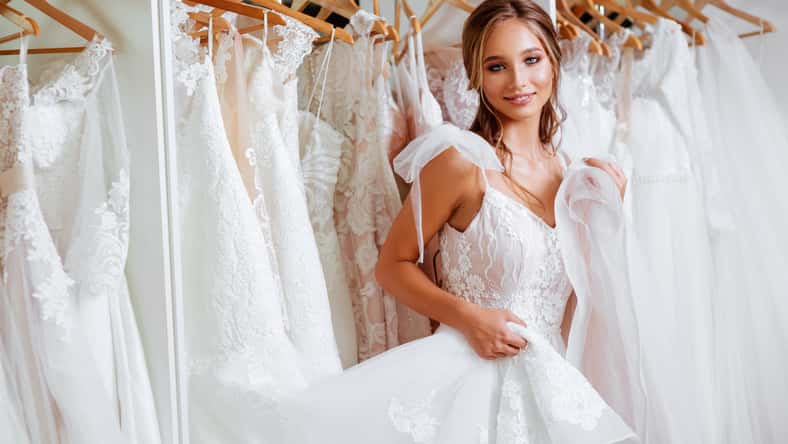Beautiful bride is trying on an elegant wedding dress in modern wedding salon