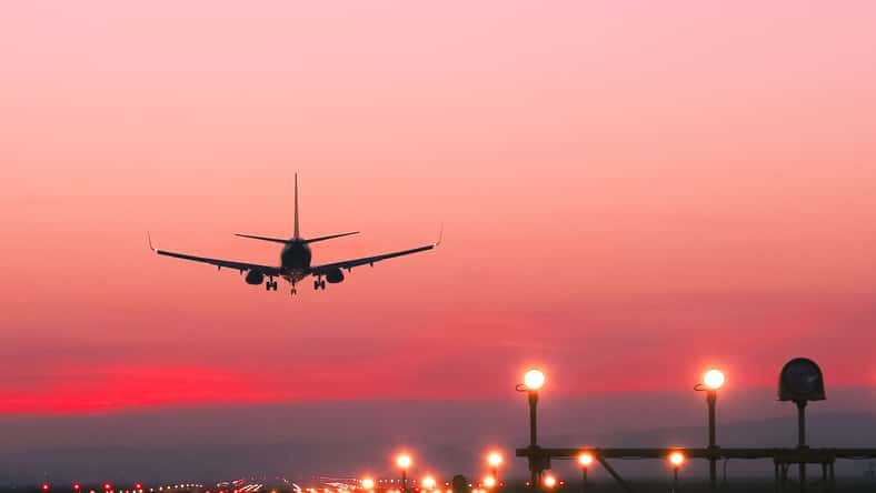 Plane landing at runway on the background of red sunset