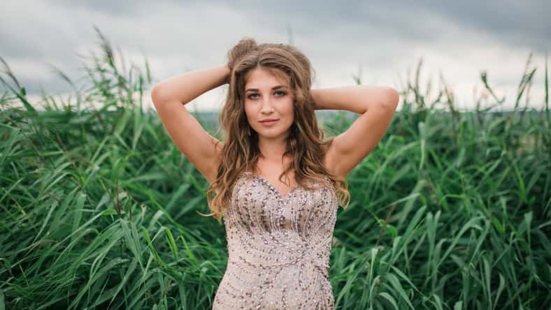 beautiful young girl in a summer dress in a field on a background of green grass