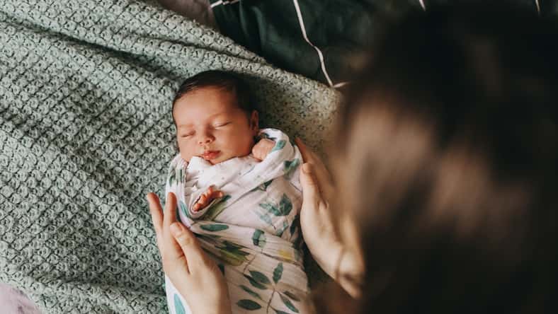 young mother swaddling a newborn baby