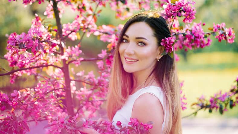 Beautiful girl with color hair Ombre is in blossoming pink tree in the spring and . Beautiful eyes and a pretty face.