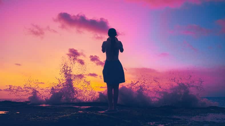 Silhouette of a girl on the shores of the Indian Ocean during a saturated sunset