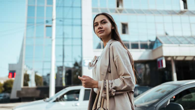 Young busy business woman with long dark hair in a white blouse walks around the city for a meeting