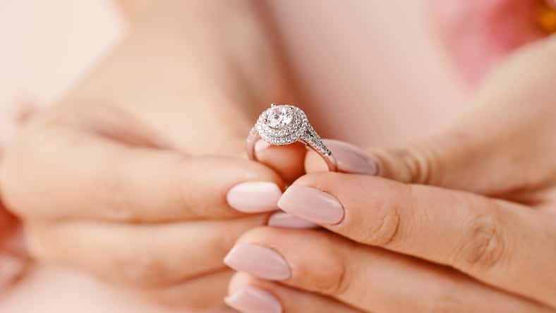Close up of woman's hand holding elegant diamond ring.