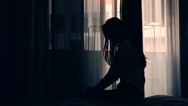 Sad young woman sitting on the bed in the bedroom, People with depression concept.