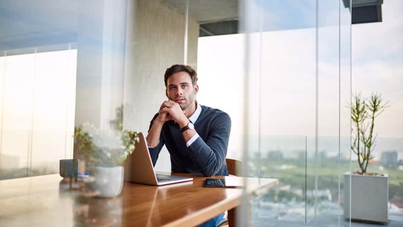 Young businessman deep in thought while sitting at a table at home and working on a laptop