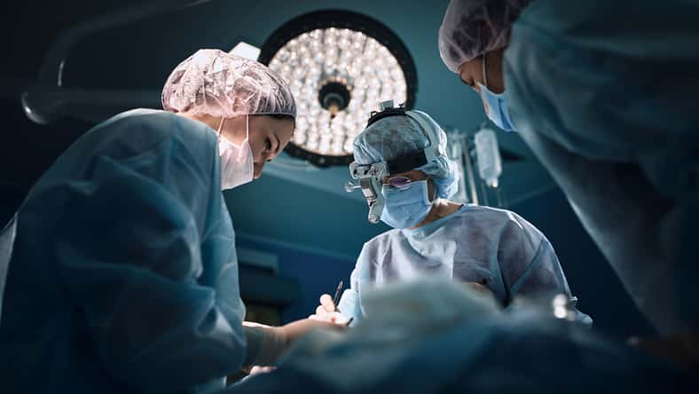 Medical team in the operating room, dark background. The theater of the operating room, an international team of professional doctors in a modern operating room are conducting an operation. Saving lives, modern medicine, blue blue light.