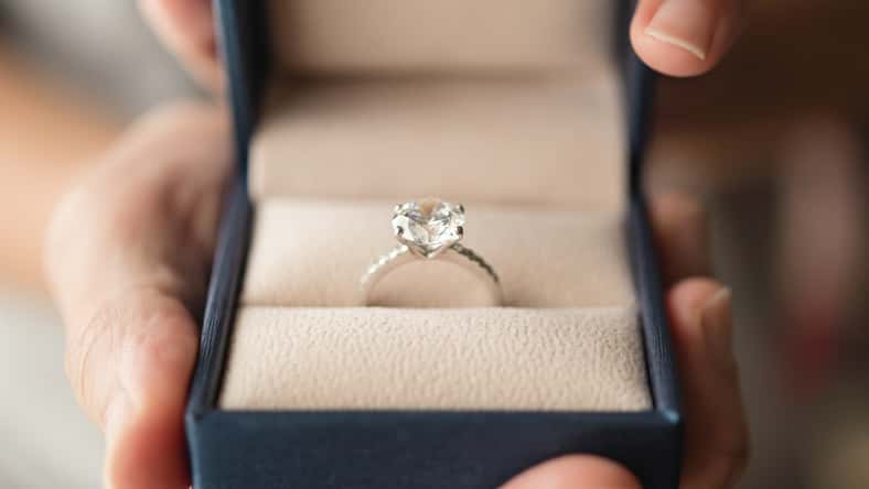 hands holding diamond ring in jewelry box