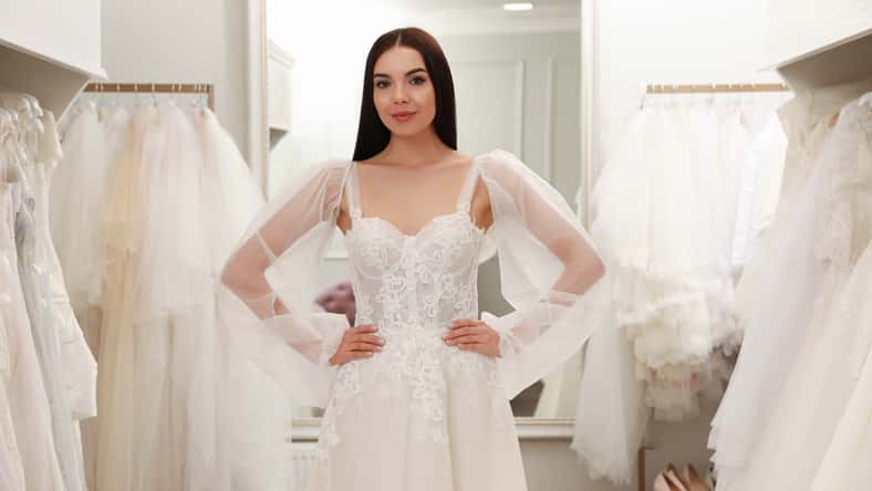 Woman trying on beautiful wedding dress in boutique