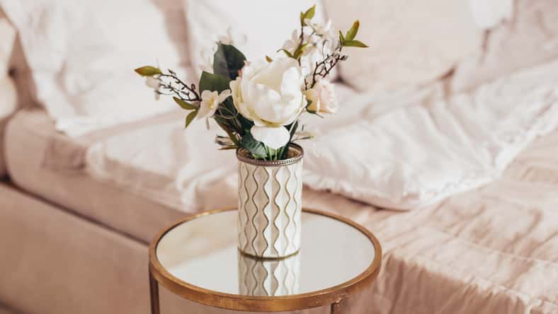 Beautiful bouquet of flowers in vase on bedroom background