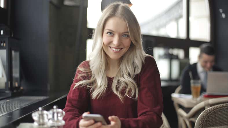 smiling young woman with smartphone in a cafe
