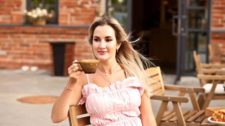 Beautiful woman drinking coffee in a cafe and eating croissant.