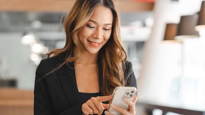 Asian businesswoman in formal suit in office happy and cheerful during using smartphone and working