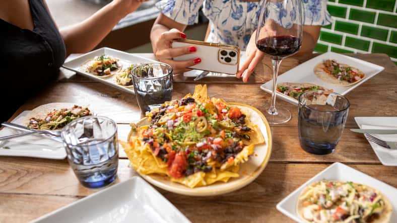 Close-up of woman photographing Mexican food at restaurant table