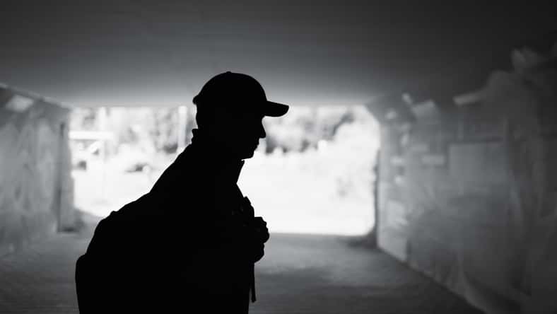 Silhouette of man walking alone in the city caring backpack
