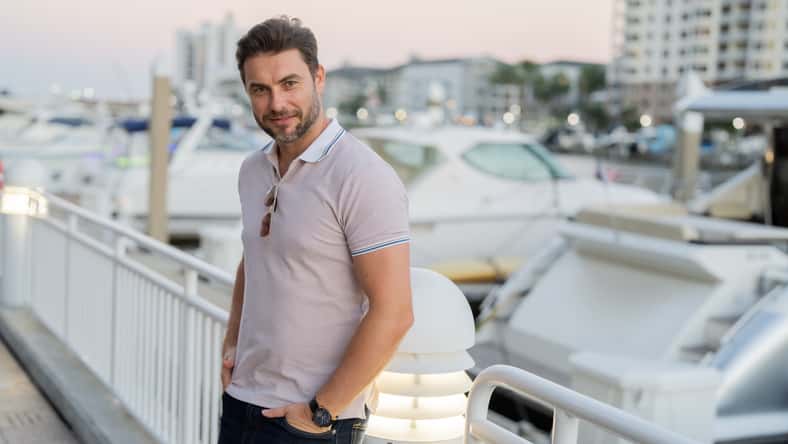 Portrait of handsome male model outdoor. Stylish man dressed in polo. Fashion male posing on the street background. Urban style. Young man walk through the city. Wealthy businessman posing next to office building