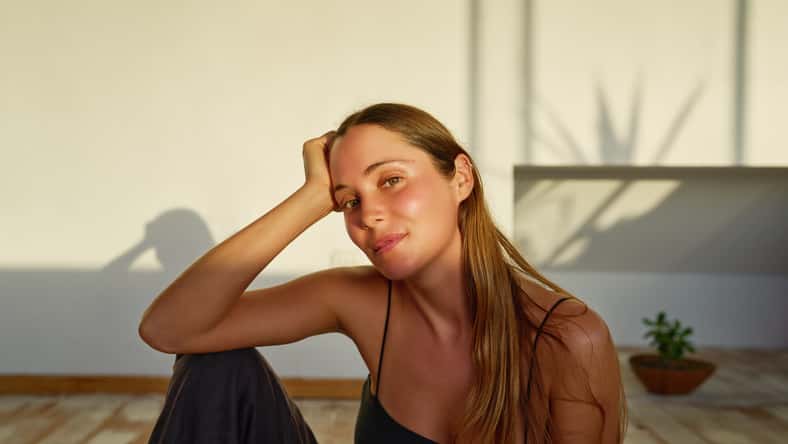 beauty portrait young caucasian woman sitting on the floor posing and smiling carefree indoors