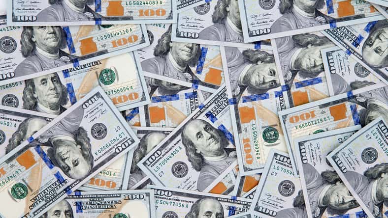 Financial background of American 100 dollar bills scattered randomly with the portrait of Benjamin Franklin uppermost, closeup view