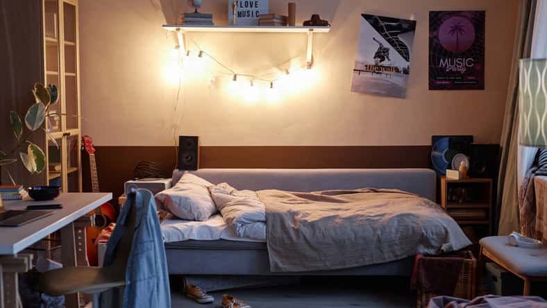 Background image of teens room interior with comfortable unmade bed and posters on wall