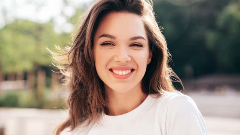 Portrait of young beautiful smiling woman in trendy summer clothes. Sexy carefree woman posing in the street at sunset. Positive model outdoors at sunny day. Cheerful and happy. Closeup